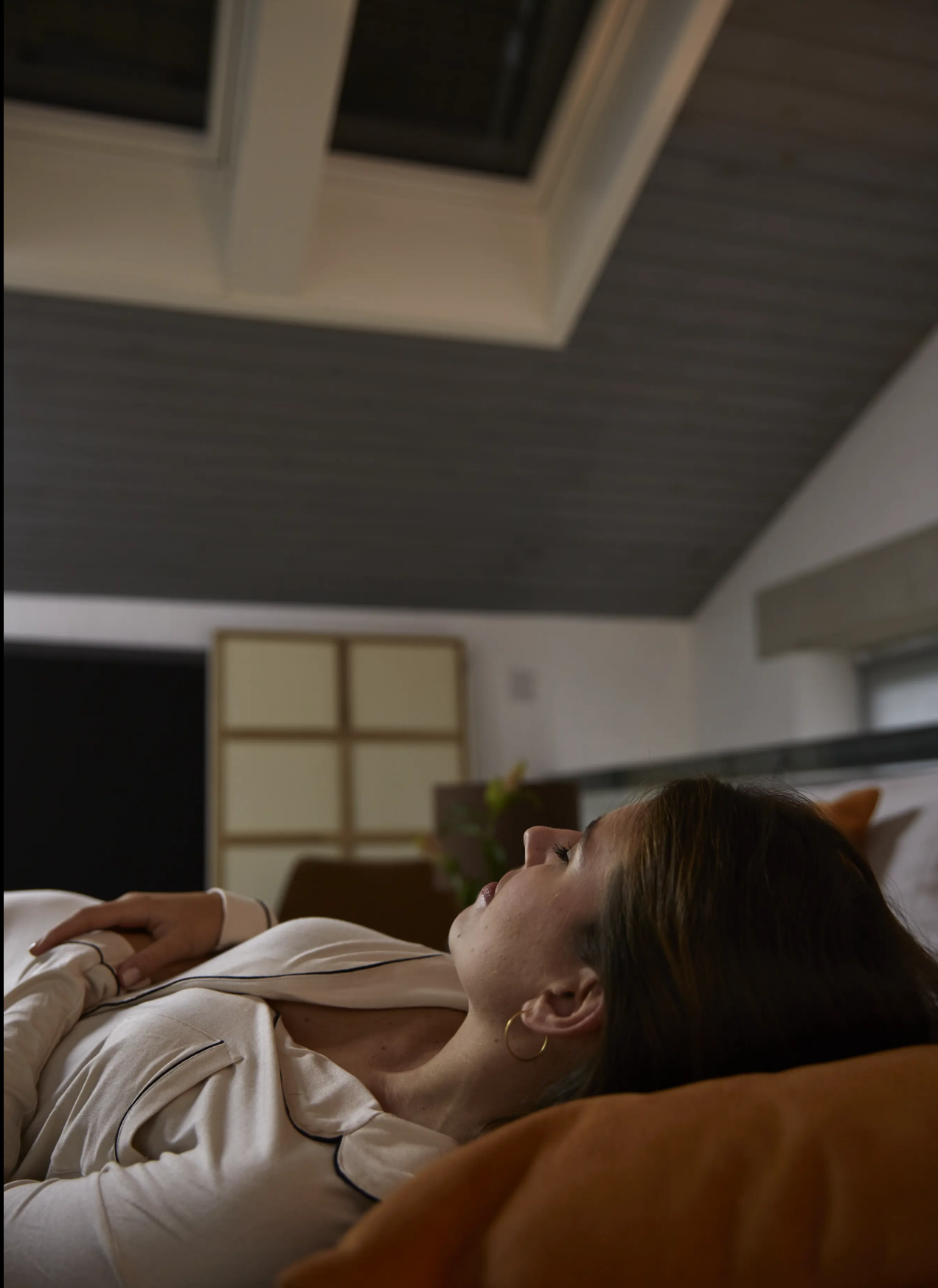 A woman is sleeping peacefully under a venting skylight