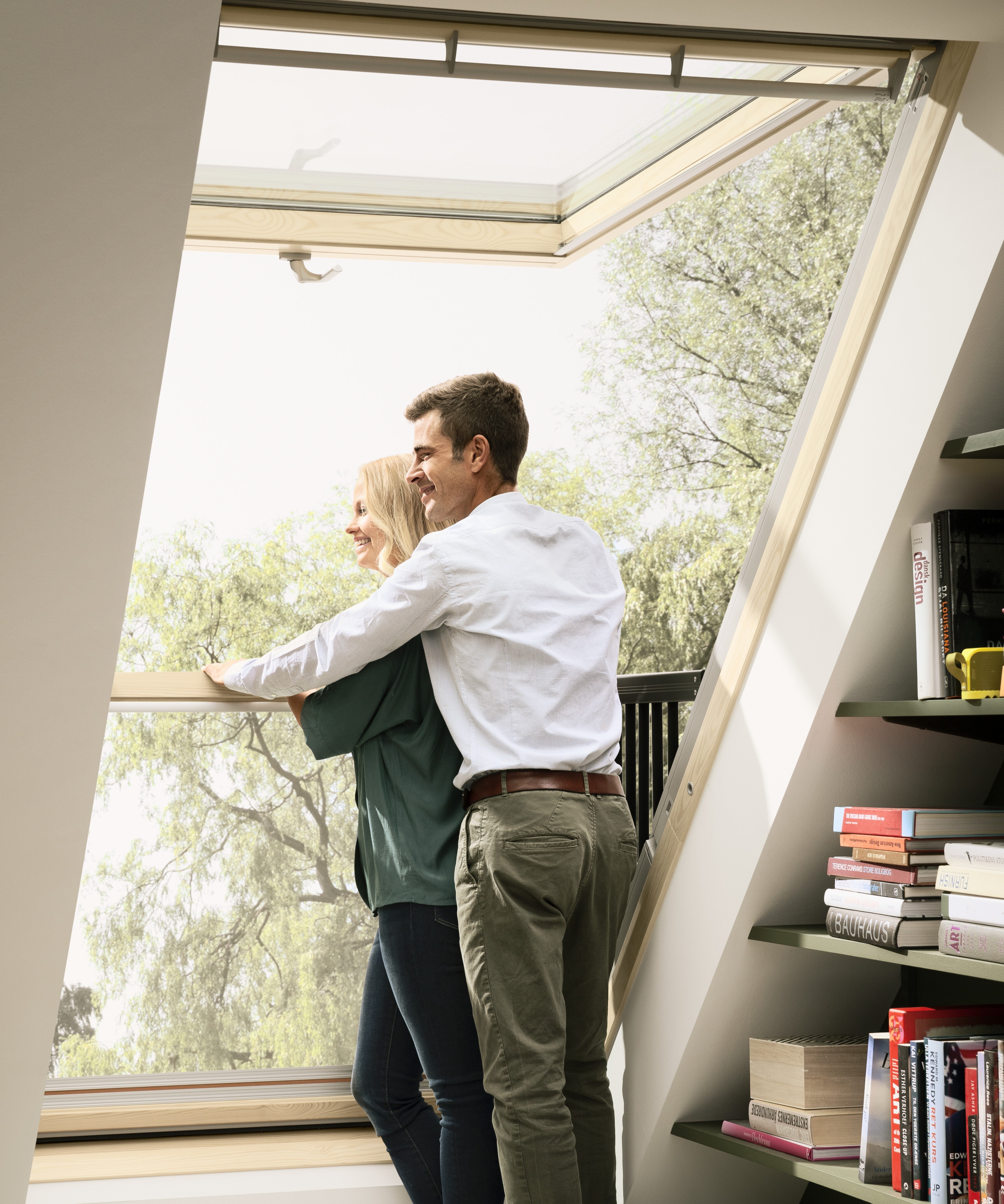 A couple hold each other inside the VELUX Balcony roof window as part of an eco-friendly home